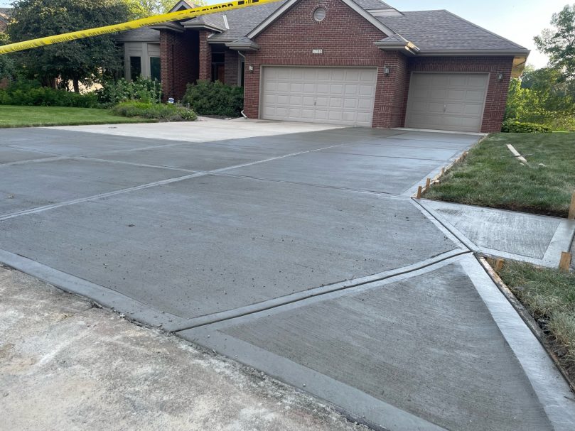 Three-Car Concrete Driveway Newly poured driveway with a smooth, fresh concrete surface that shows signs of still drying.