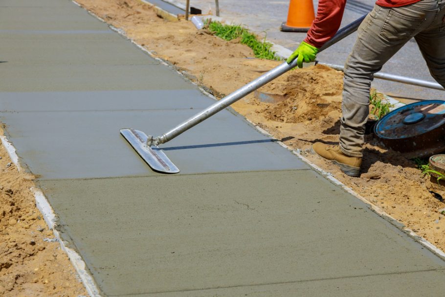 Hard at work! Worker smoothing out freshly poured concrete for a sidewalk