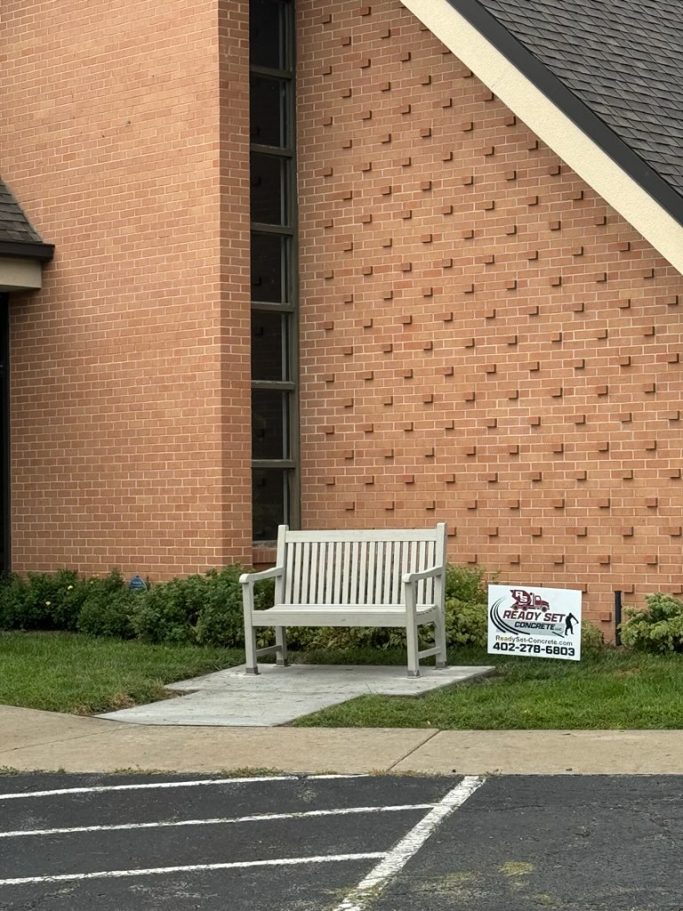 A finished sidewalk extension project with an added bench for a church