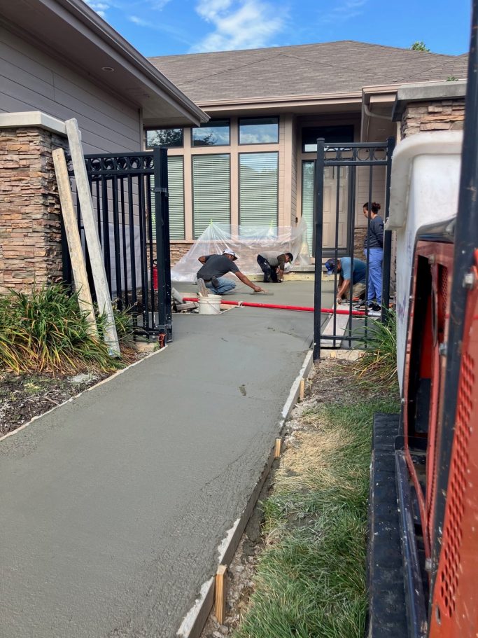 Progress on front entry home project. Workers are smoothing the freshly poured concrete at the front of the home. 