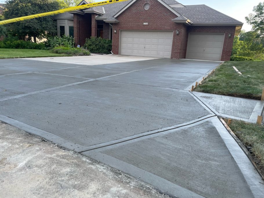 Newly poured driveway with a smooth, fresh concrete surface that shows signs of still drying.