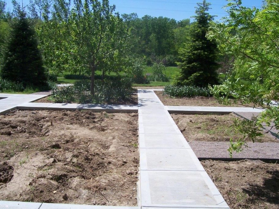 Concrete garden pathway leading into a garden and going in all directions to view different sections of the garden