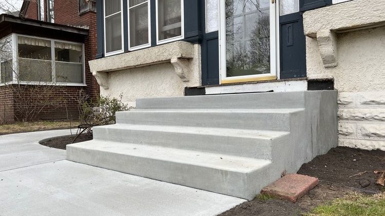 A new 4 step concrete staircase leading up to a homes front door entry