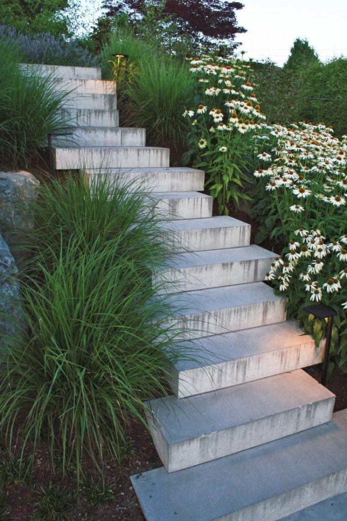 Concrete Stairs that are surrounded by a garden of greenery and white flowers