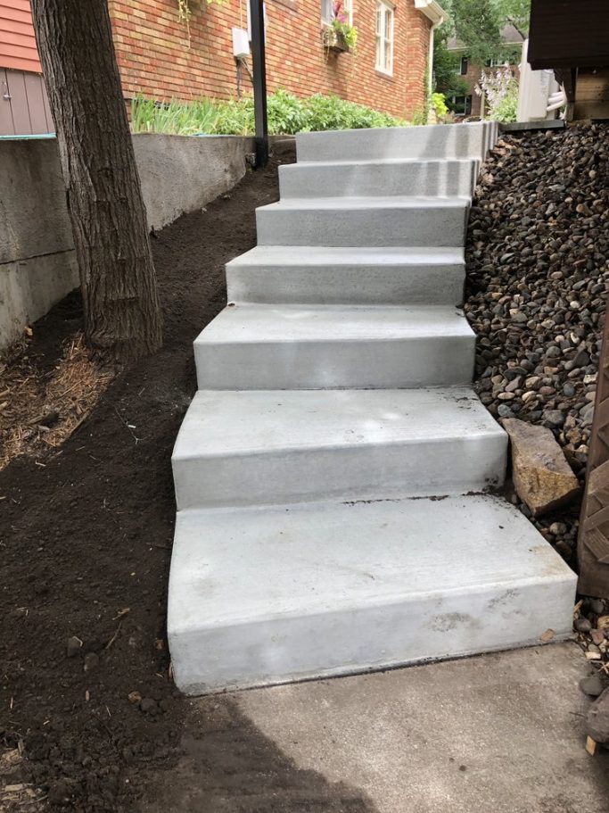 Outdoor concrete staircase leading into the backyard from the side of the house